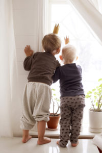 Kaksi pientä lasta katsoo ulos ikkunasta